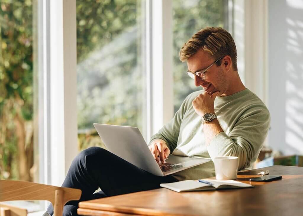 Young professional comfortably sitting at a table while using laptop computer