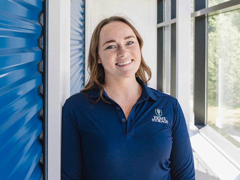 Prime employee smiling while standing in hallway next to indoor storage unit